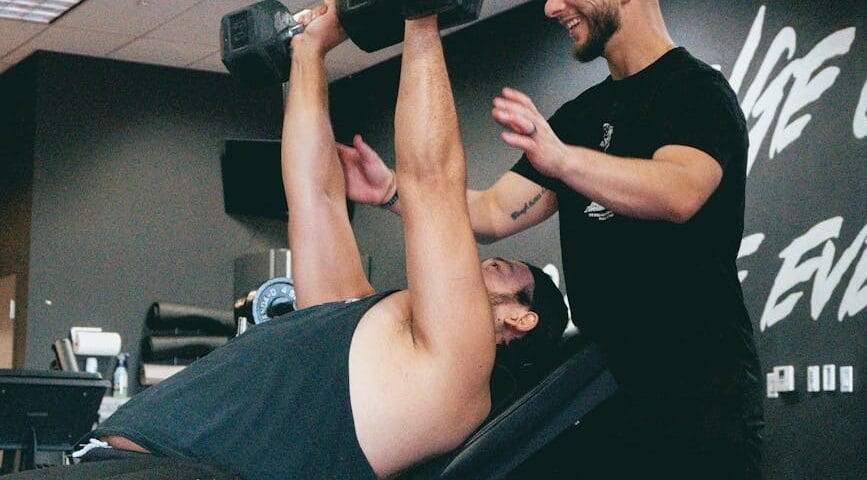 personal trainer assisting with incline dumbbell press