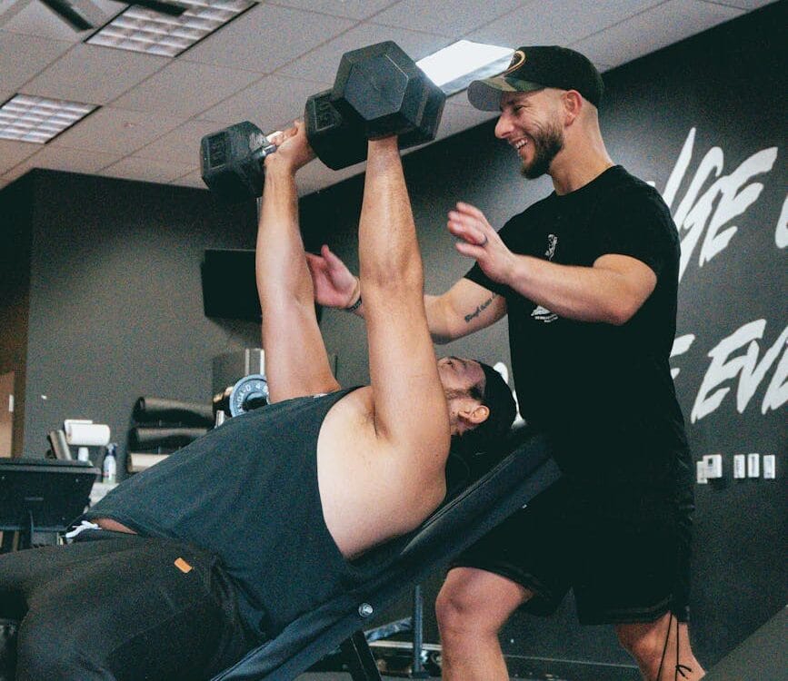 personal trainer assisting with incline dumbbell press